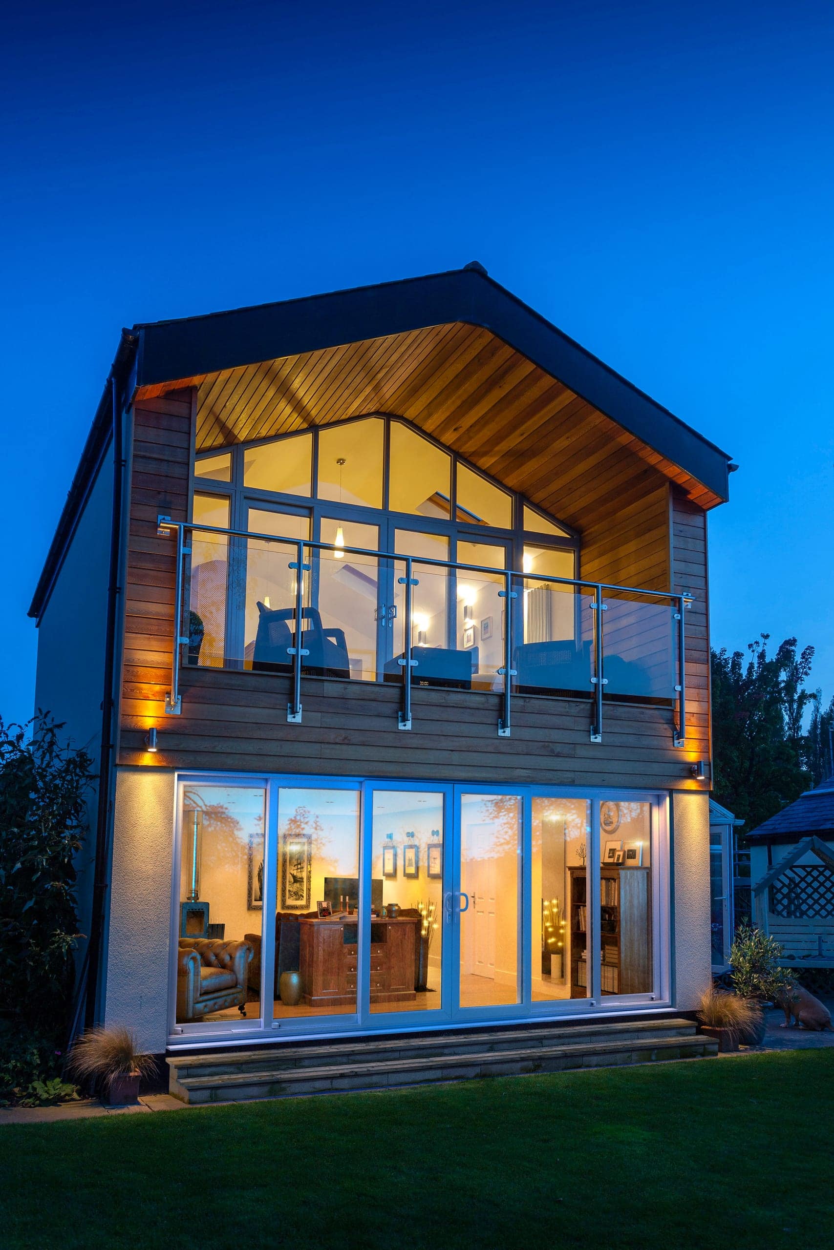 Modern home lit at dusk with full-height glazing